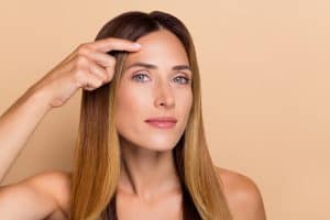 Woman points to her smooth forehead months after her Botox treatment.