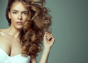 Beautiful woman with long flowing hair has proportional breast implants.