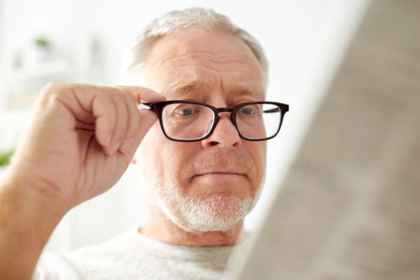 Male over the age of forty with Presbyopia tries on eyeglasses.