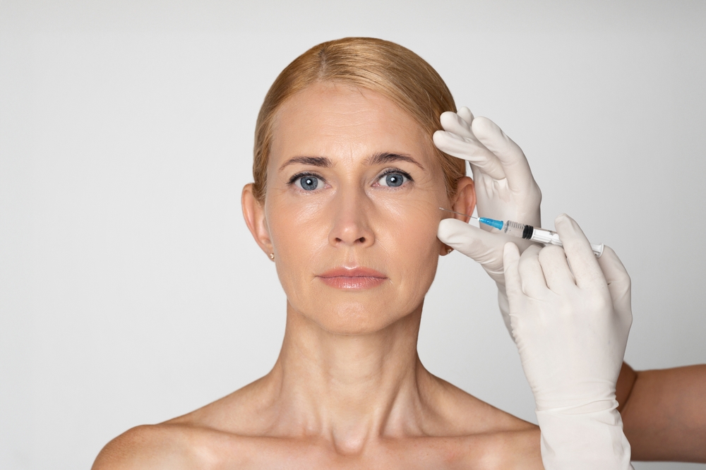 Woman stares straight ahead during a filler injection prior to her scheduled facelift