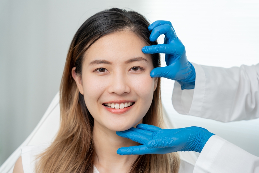 Young Asian woman smiles during an eyelid surgery consultation with her plastic surgeon