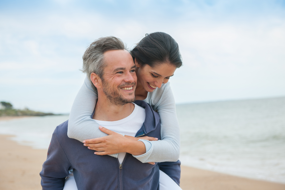 Couple with revitalized energy walks down a beach following BHRT treatment.