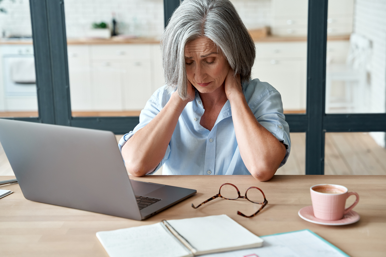 Mature business woman feels tired at her job due to chronic fatigue.