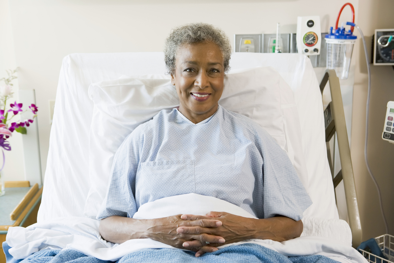 Woman recovering from surgery smiles in her bed, already feeling better.