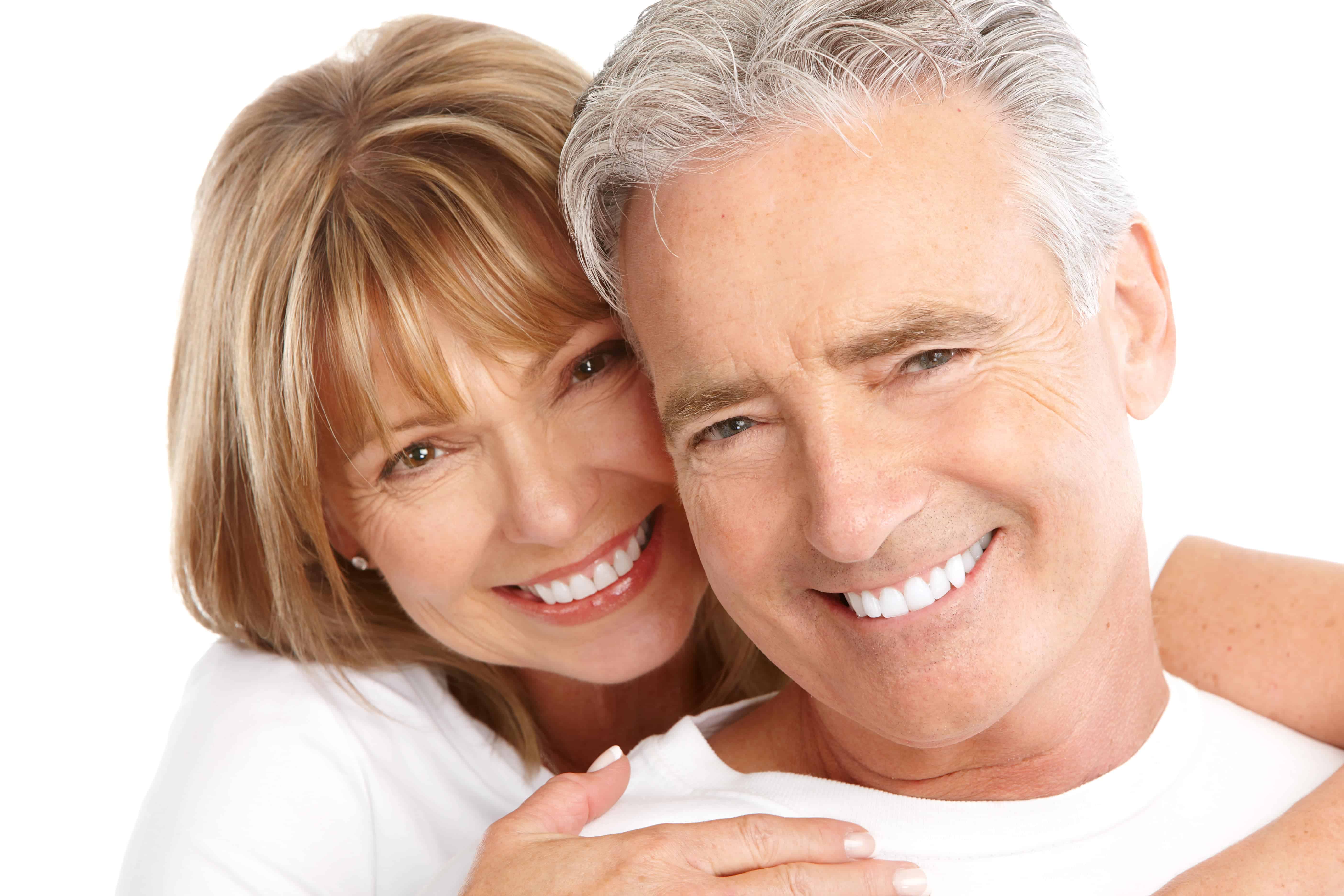 Attractive mature couple show wide smiles after improving their teeth with full mouth reconstruction