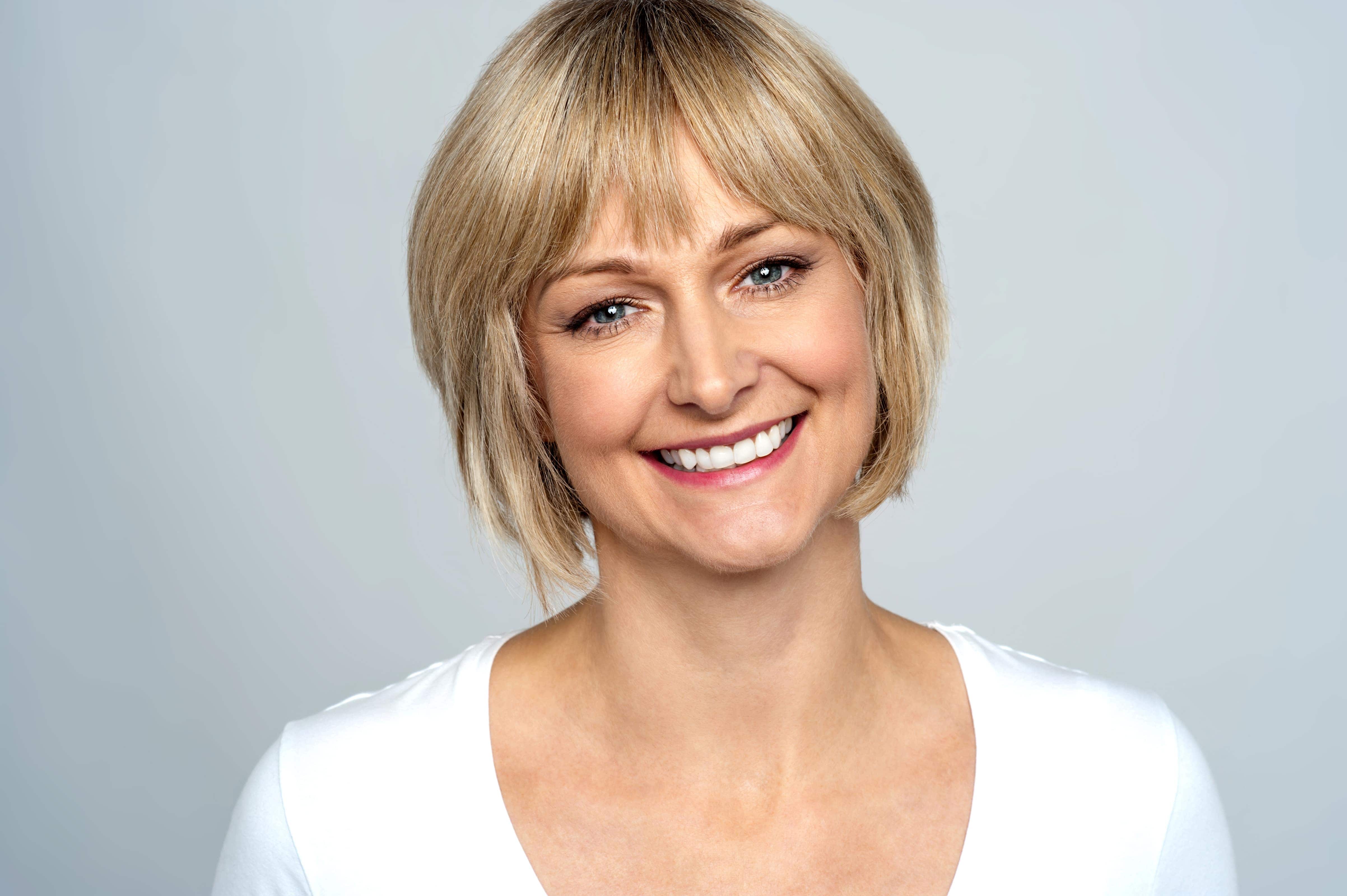 Middle aged woman has perfect white teeth after smile makeover cosmetic treatments