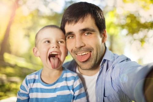 father and son laughing sticking tongues out