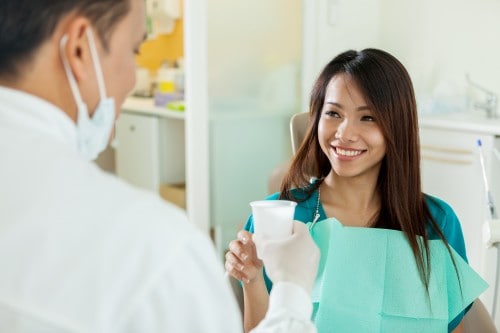 dentist handing patient a glass of water