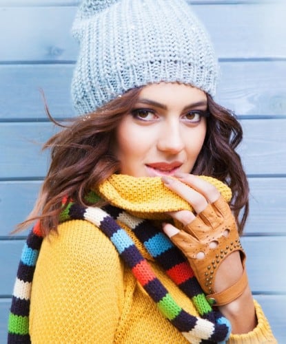 Woman in yellow sweater pulling collar down from covering her face