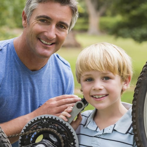 Father and son smiling while fixing a bike