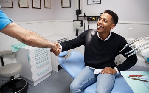 young man shaking hand with his dentist after treatment