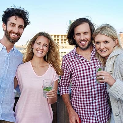 Two couples looking at camera and smiling holding glasses of water with mint