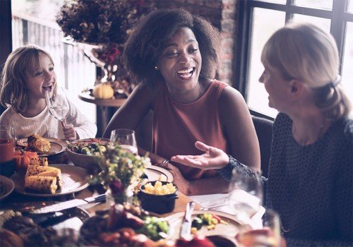 Family laughing together at Thanksgiving dinner table