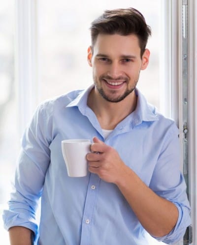Man happily drinking coffee and smiling