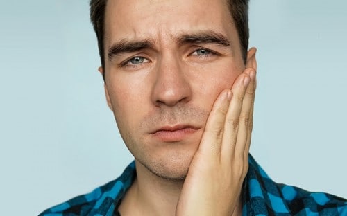 Man holding his cheek from discomfort