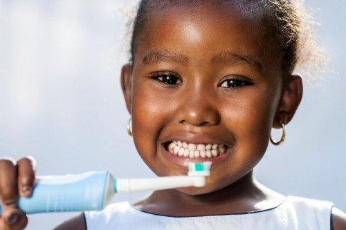 little girl holding up an electric toothbrush