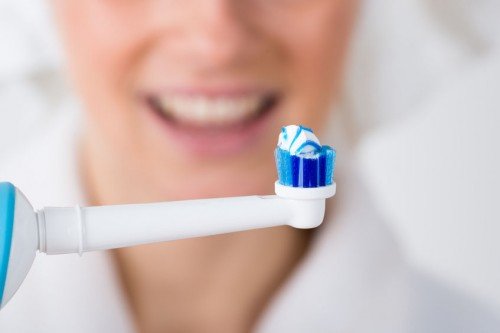 woman holding an electric toothbrush in front of her smile