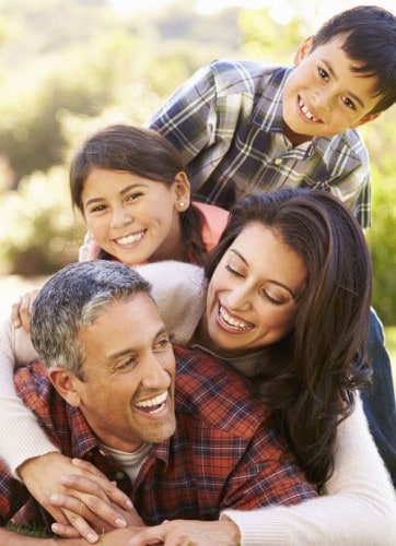 Family piled on dad laughing in park