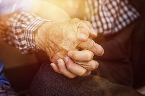Elderly person and young person hold hands closeup