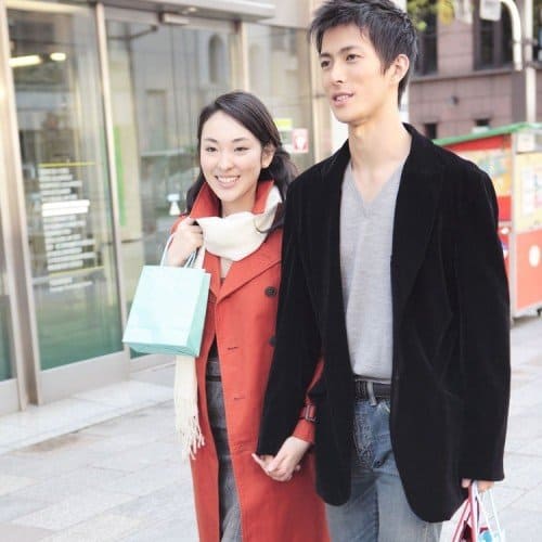 young couple walking down street shopping smiling holding hands