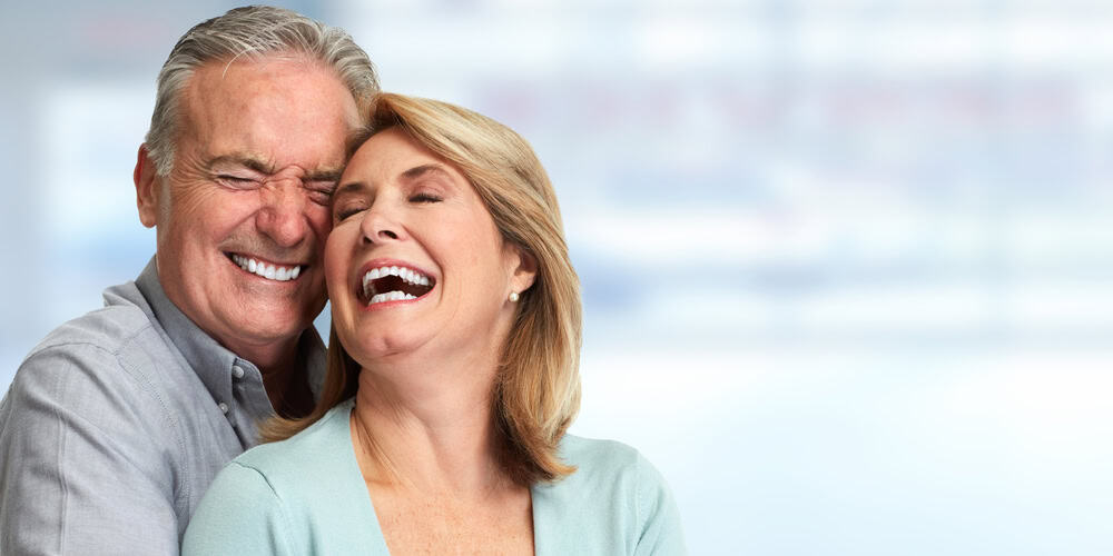 Man and woman with healthy smiles after tooth replacement implants in Seattle, WA