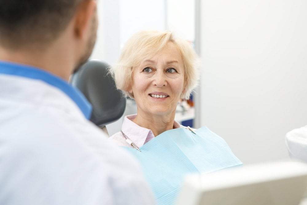 Woman talking to dentist about guided biofilm therapy in Seattle