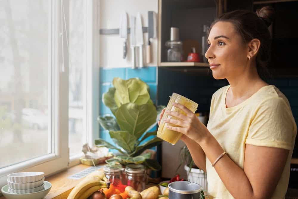 Woman drinking a smoothie after implant surgery in Seattle