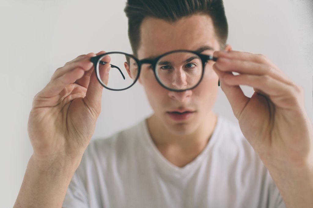 Man holds glasses in front of his face, contemplating LASIK