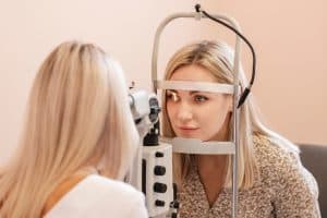 Blonde woman undergoes an eye exam to examine early signs of ocular trouble
