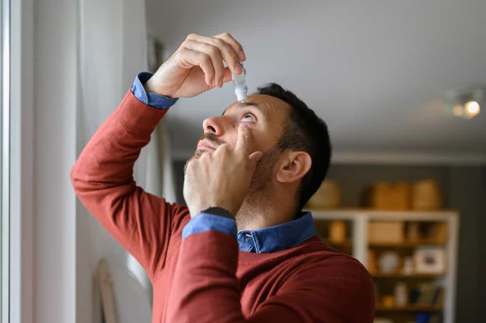 Man puts eyedrops into his eye when experiencing dry eye symptoms.